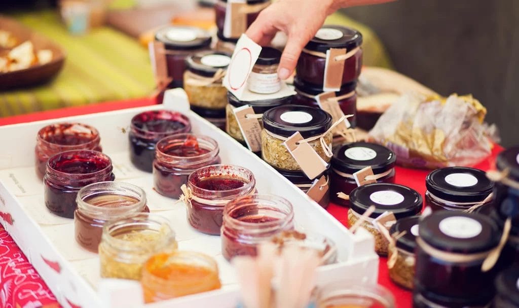 Close-up look at homemade jams and preserves on display in a vendor booth.