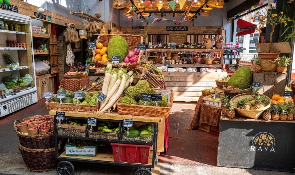 A fresh fruit and vegetable vendor has their booth set up and fully stocked for a market event.