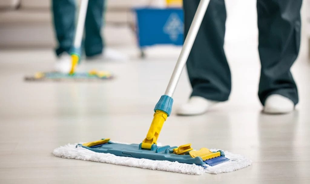 Close-up of a mop on the floor held by a cleaning professional while sanitizing the floors.