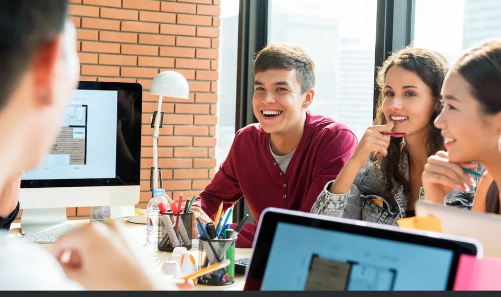 Young group of college students smiling and looking at their educational advisor in a meeting.