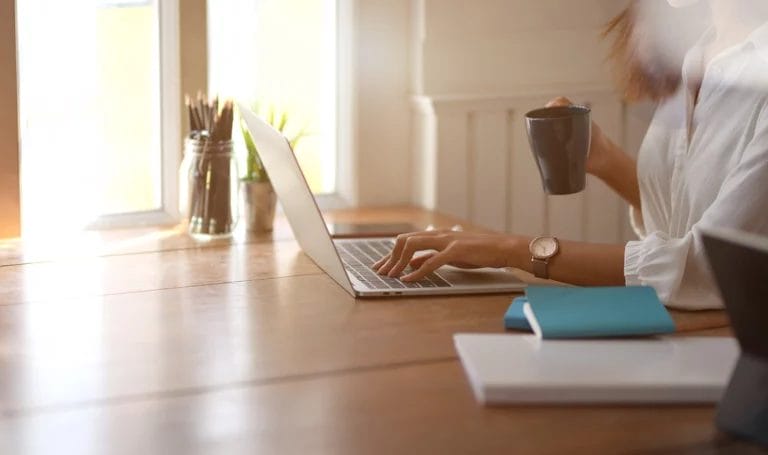 Young businesswoman working with laptop computer and drinking a cup of coffee.