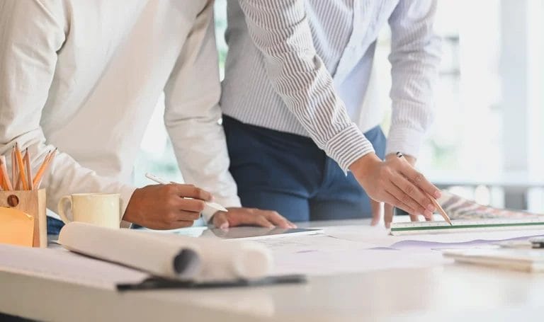 Closeup shot of two business consultants drawing up plans together on a desk.