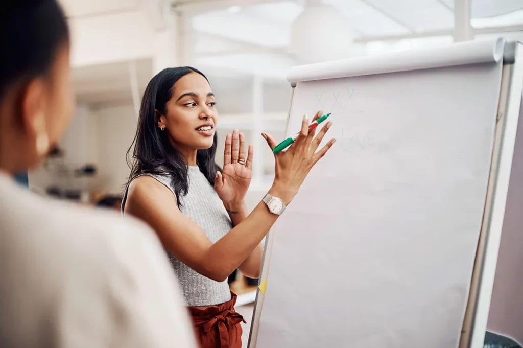 A female life coach posed to write on a large sheet of white paper during a training session.