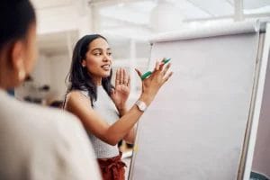 A female life coach posed to write on a large sheet of white paper during a training session.