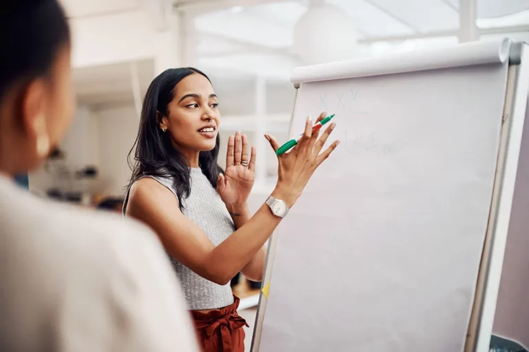 A female life coach posed to write on a large sheet of white paper during a training session.