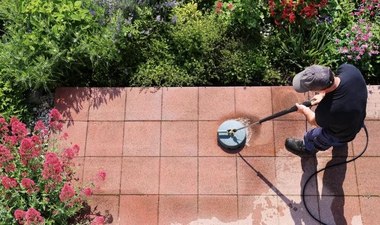 Overhead view of a professional cleaner using a special pressure washng tool to scrub a brick patio clean.