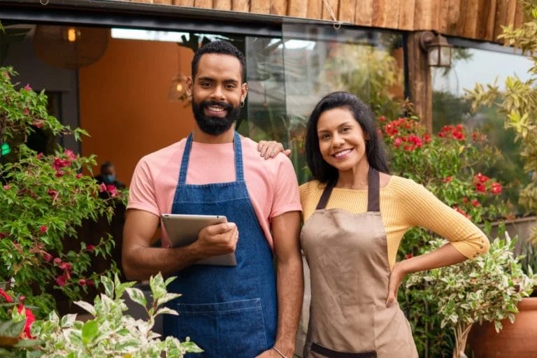 Two landscaping business owners standing near plants.