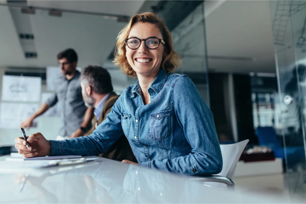 Smiling consultant sitting in a glass-walled board room during a creative meeting