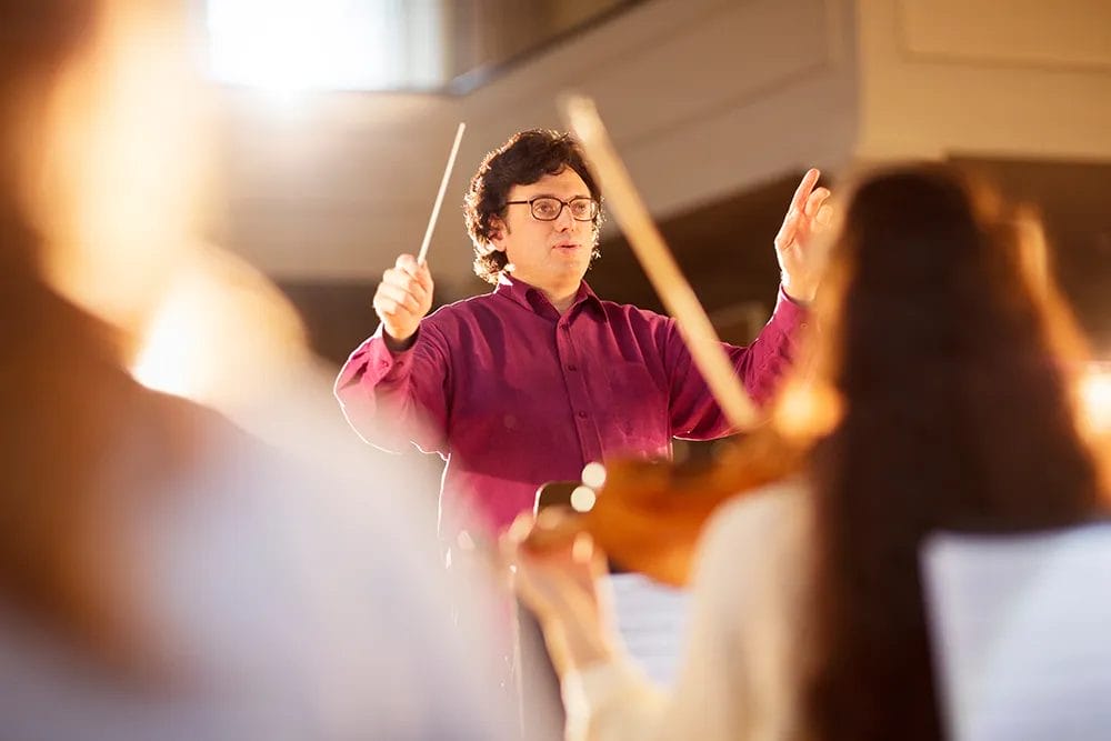 school music teacher conducts the band in an auditorium