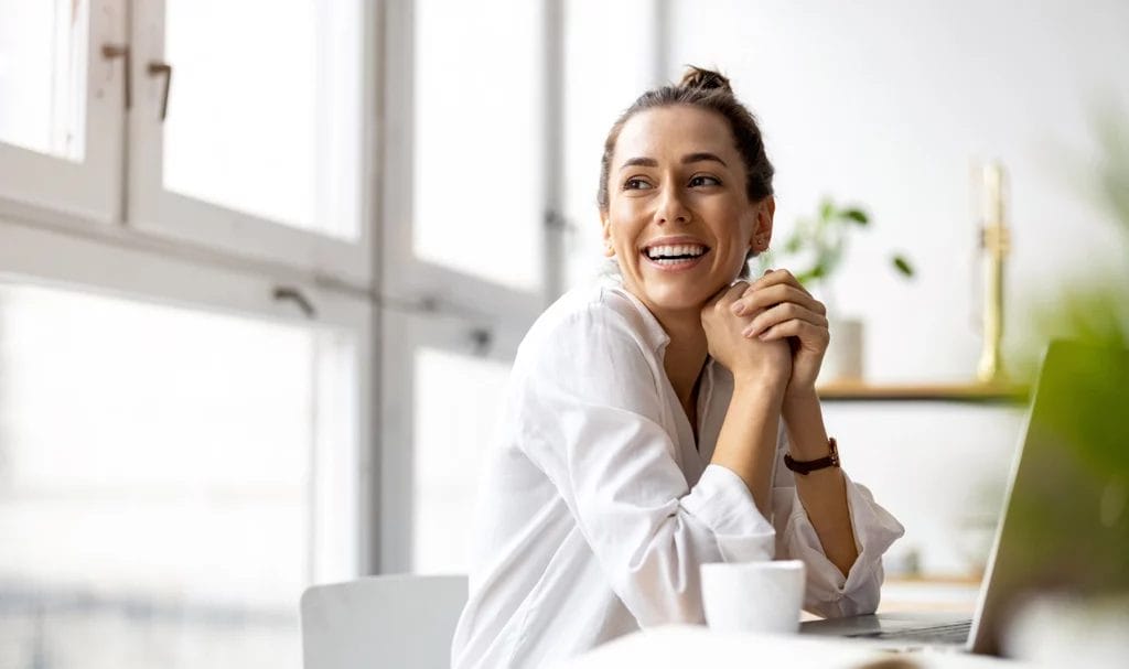 A small business owner smiling while sitting in her home office.