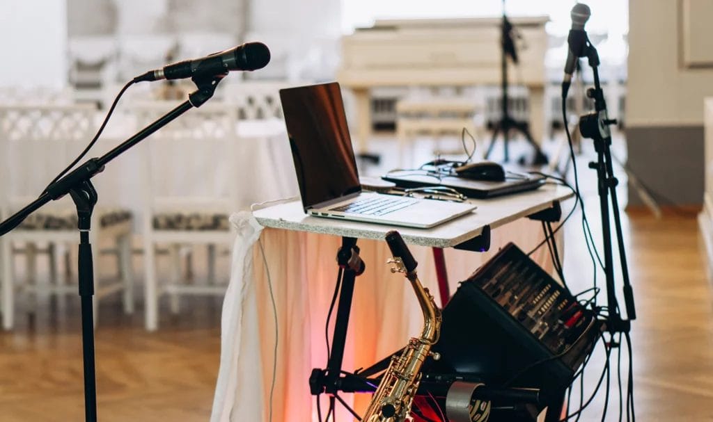 DJ equipment set up in an empty wedding hall venue, decorated for a reception, waiting for the event to begin.