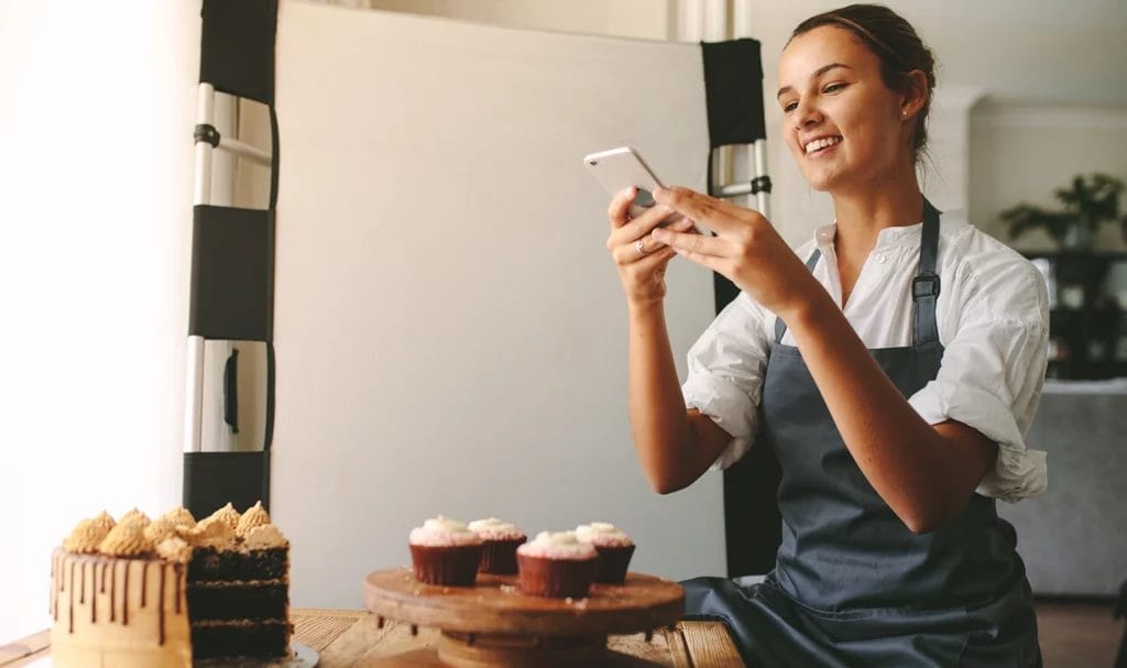 A home baker taking styled photos of her cake and cupcakes for her food blog.