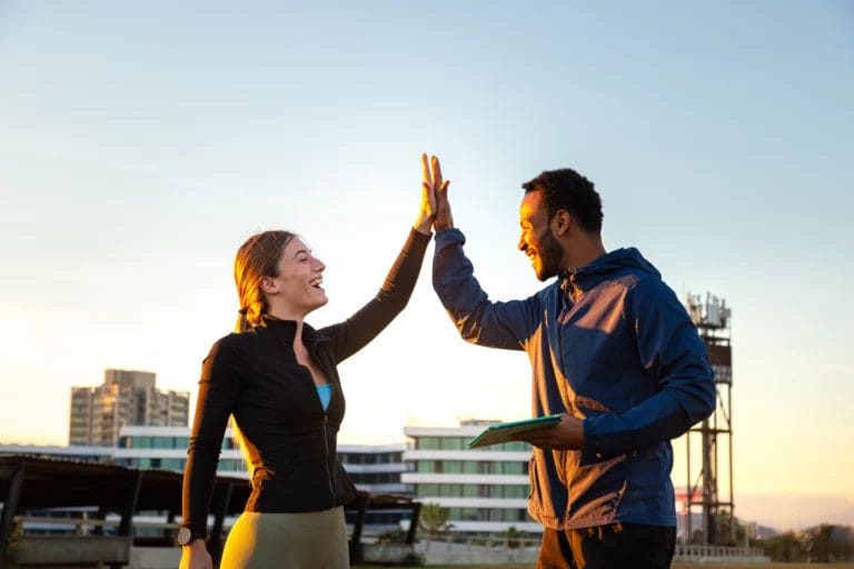 A trainer high fives a client after a morning outdoor workout.
