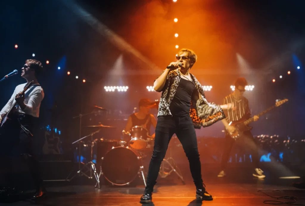 A rock band on stage with bright lights, featuring a lead singer passionately performing at the center.