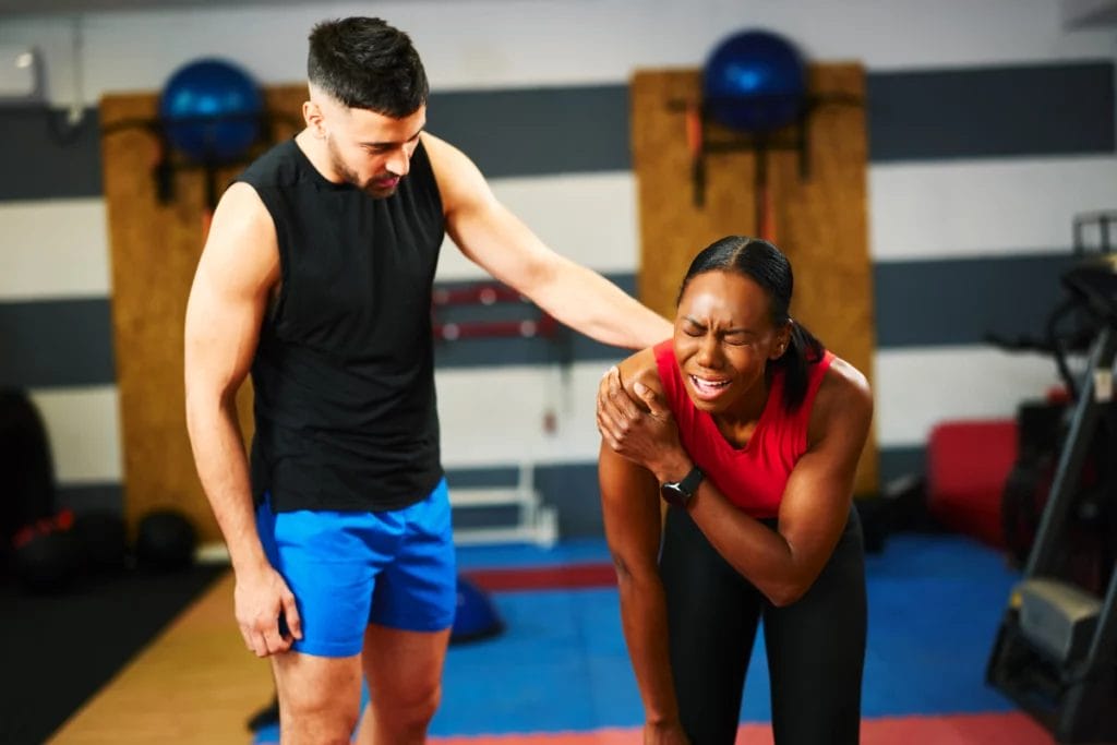 A personal trainer with a client experiencing pain in their shoulder.
