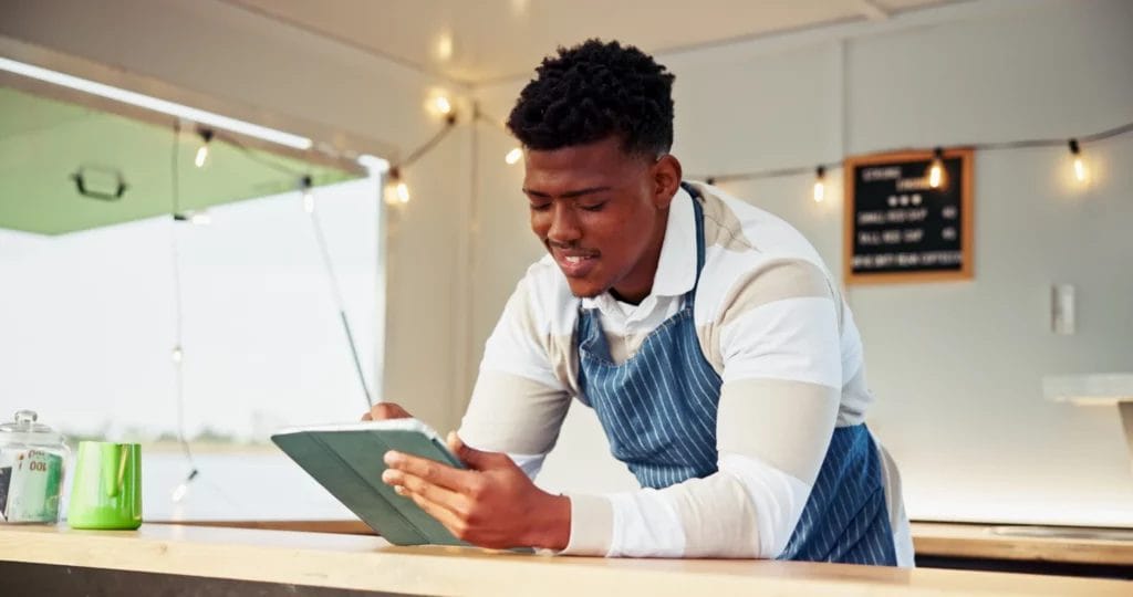 a food vendor stands at a counter writing in a notebook