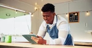 a food vendor stands at a counter writing in a notebook