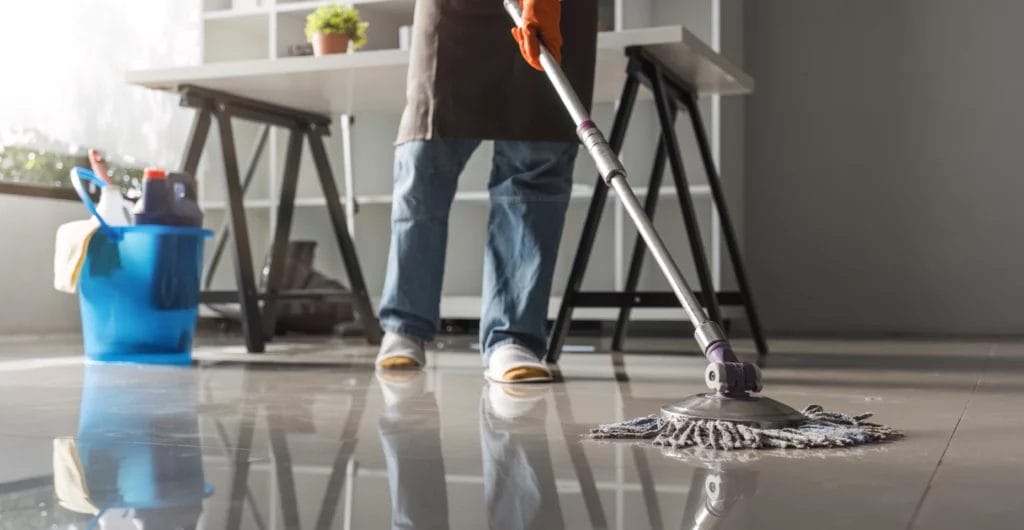 Cropped photo of a cleaner mopping a shiny office space floor.
