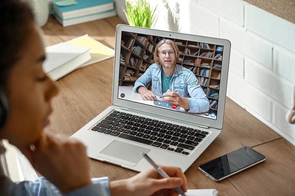 Online tutor on laptop screen teaches a student at home