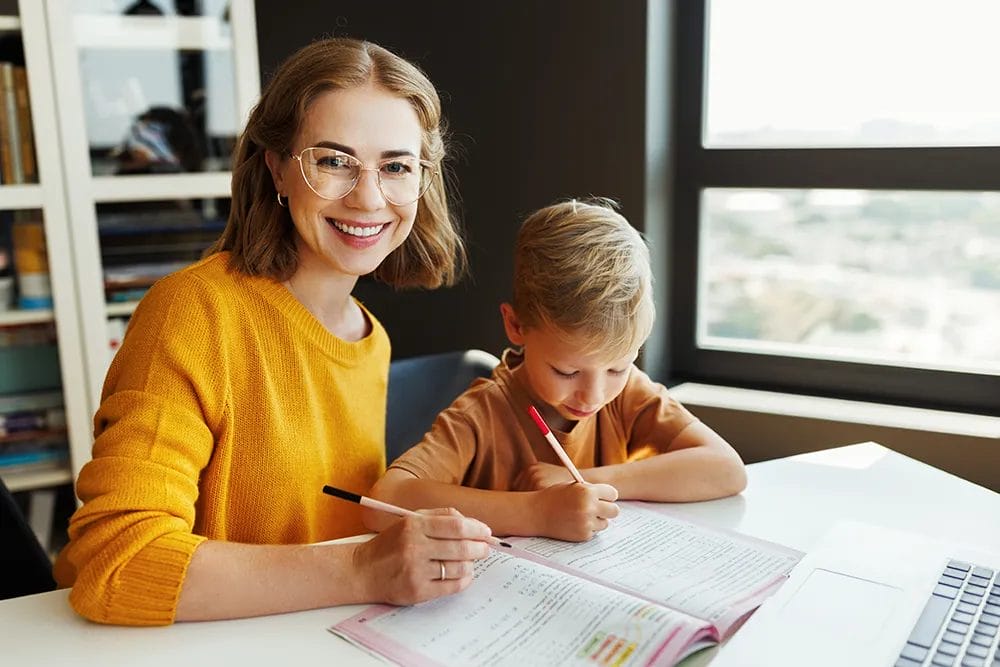 Tutor working with a young student in a workbook at home