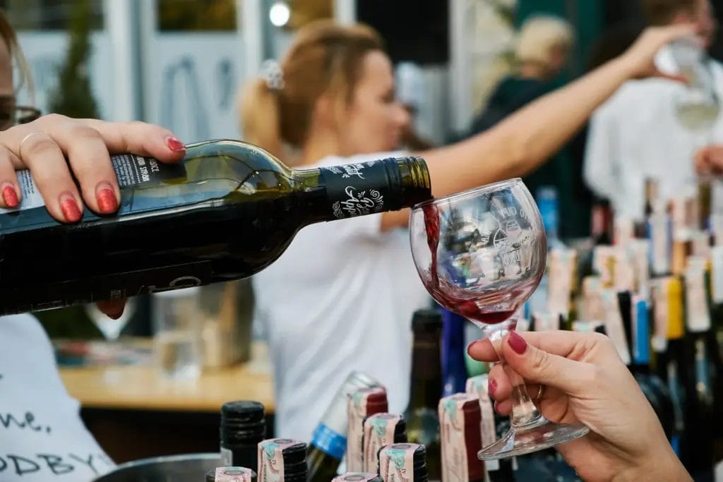 alcohol vendors pours wine into a glass at a wine festival