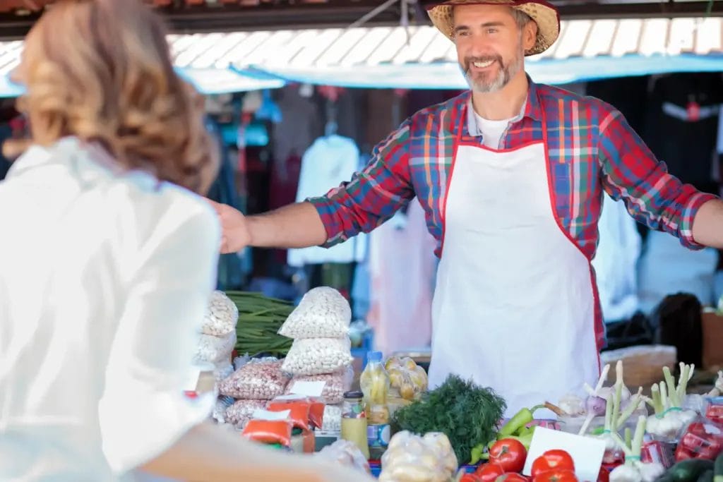 proud senior vendor selling organic vegetables and foodstuff at a local market