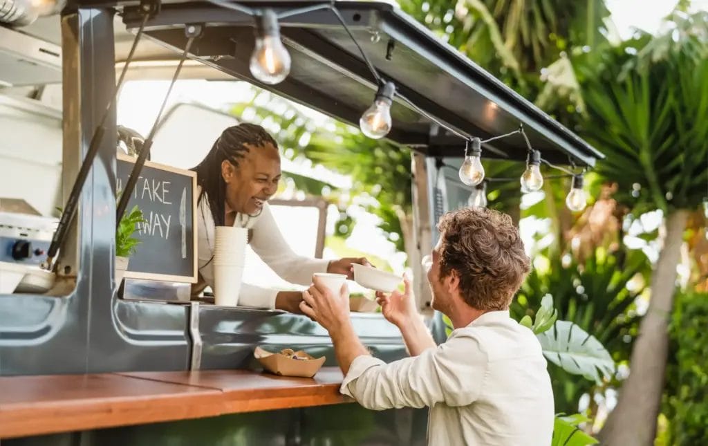 female food truck owner serving meal to a male customer