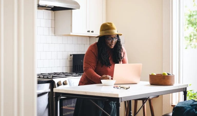 A small business owner works from a laptop in her kitchen.