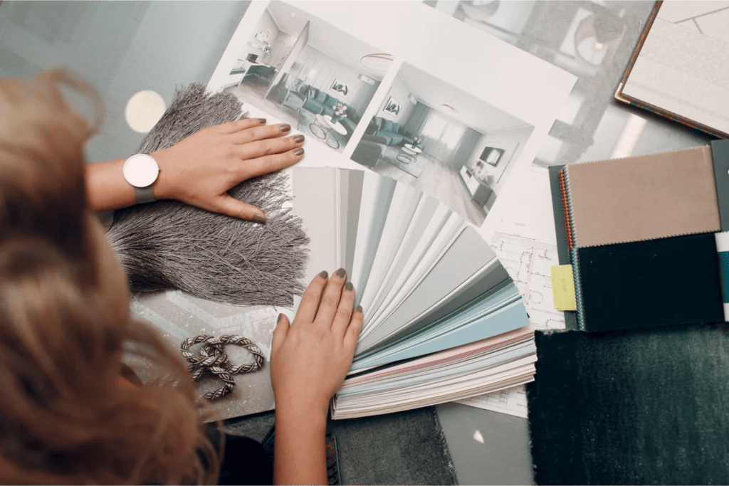 Overhead shot of an interior designer fanning out paint chips, material samples, and inspiration photos on a table.