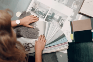 Overhead shot of an interior designer fanning out paint chips, material samples, and inspiration photos on a table.