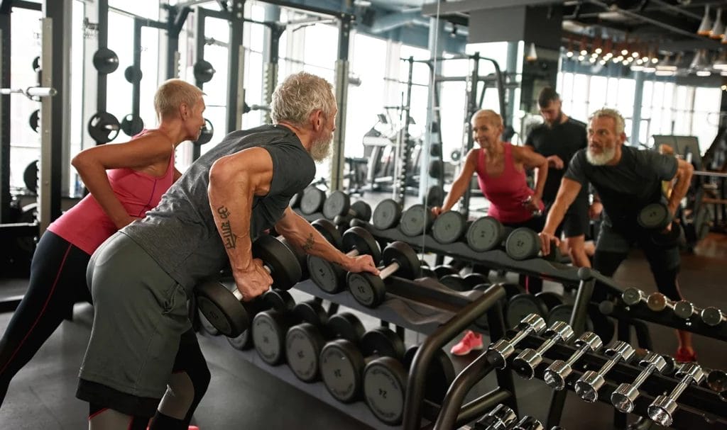 A personal trainer walks a client through the proper form for a weighted bicep exercise.