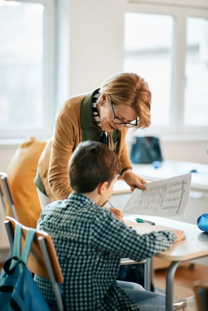 Teacher assisting student in a classroom.