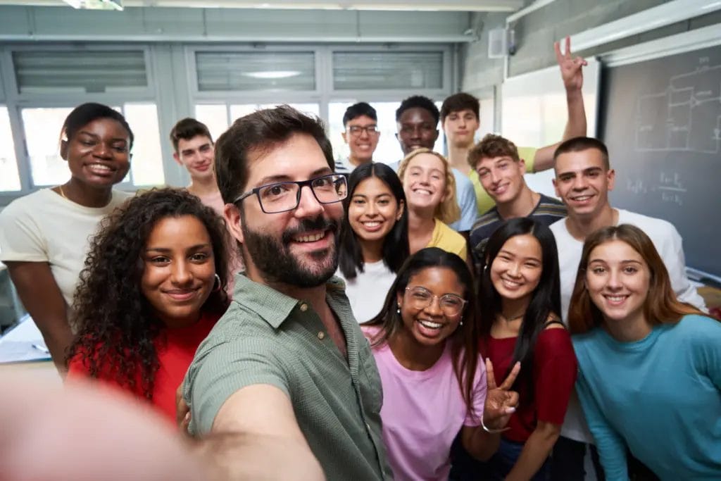 Teacher taking a selfie with his class of high school students in a classroom