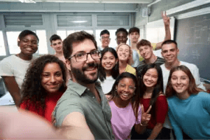 Teacher taking a selfie with his of high school students in a classroom