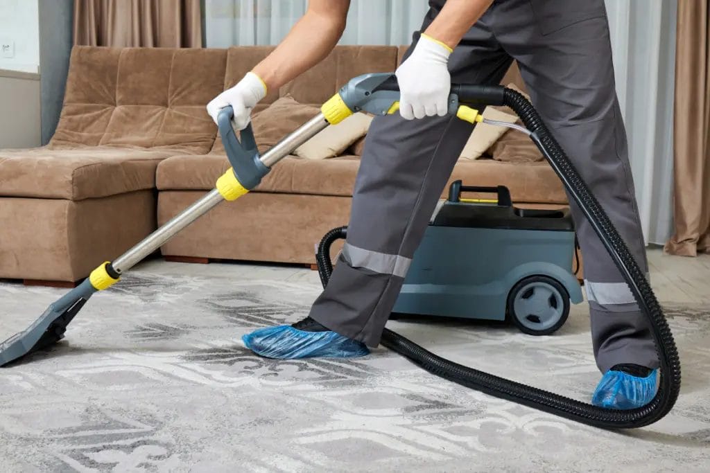 Close-up of a professional cleaner washing a rug while wearing booties and gloves.