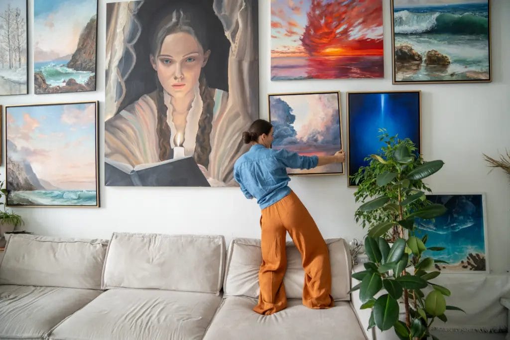 Woman hangs artwork on a large gallery wall in a home