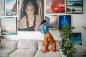 Woman hangs artwork on a large gallery wall in a home