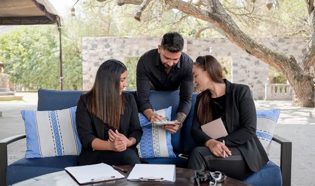 A group of event planners are reviewing paperwork at an outdoor venue.