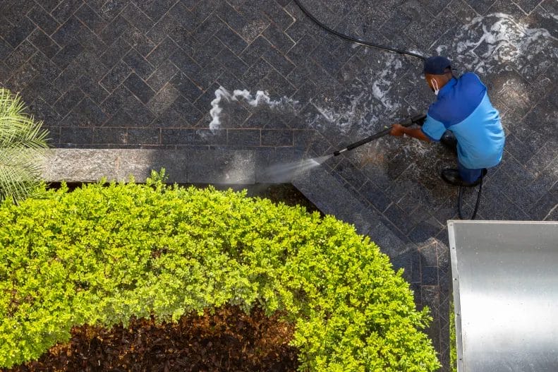 pressure washing business employee cleans a stone surface with a high pressure water cleaner