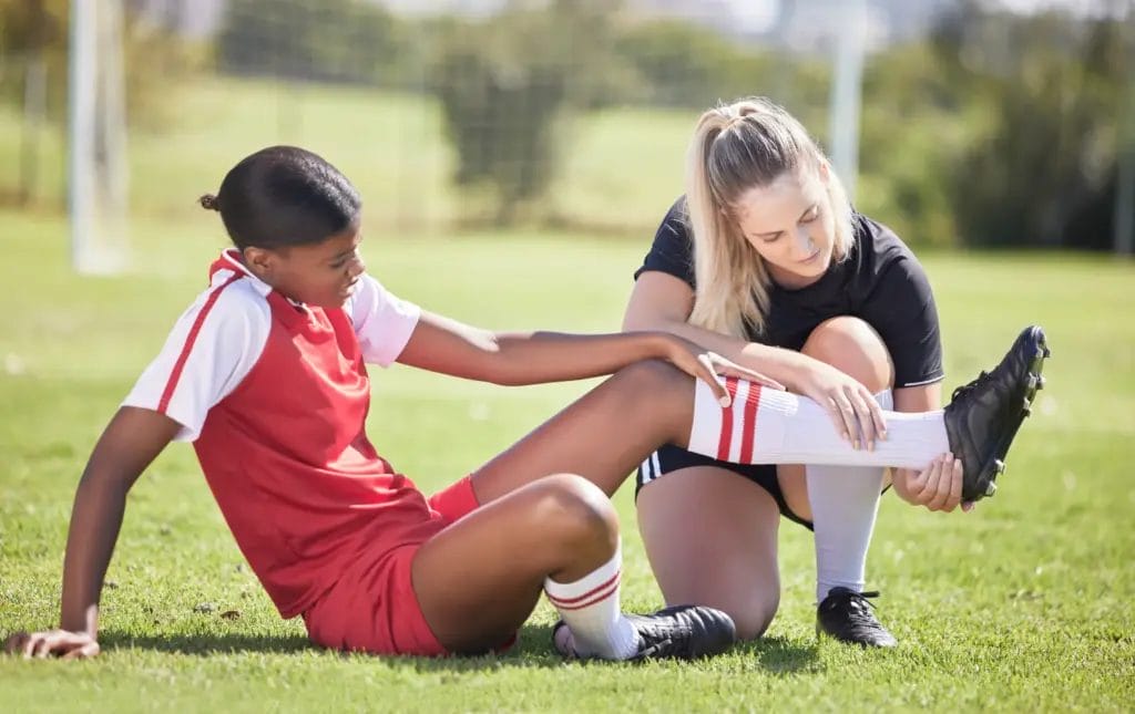 Coach attending to a youths leg injury on the field