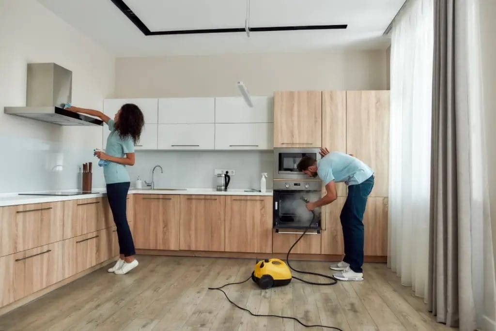 two housecleaning employees in uniform working together to clean a kitchen