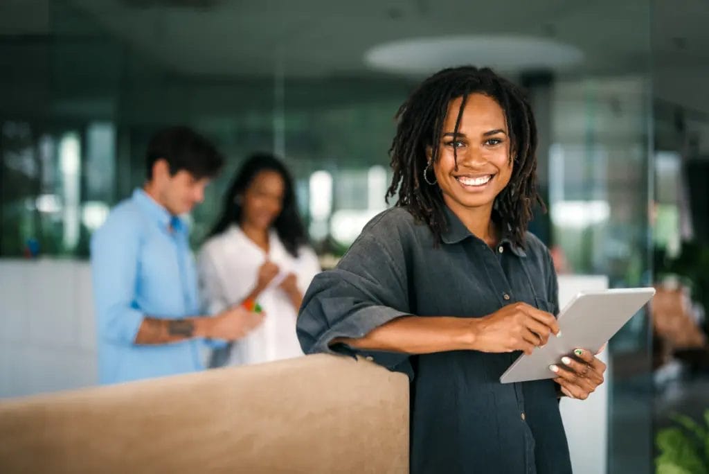 Consultant in a casual office smiling to camera and holding a tablet
