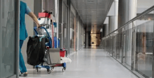 a janitor pulls a cleaning cart down an office hallway