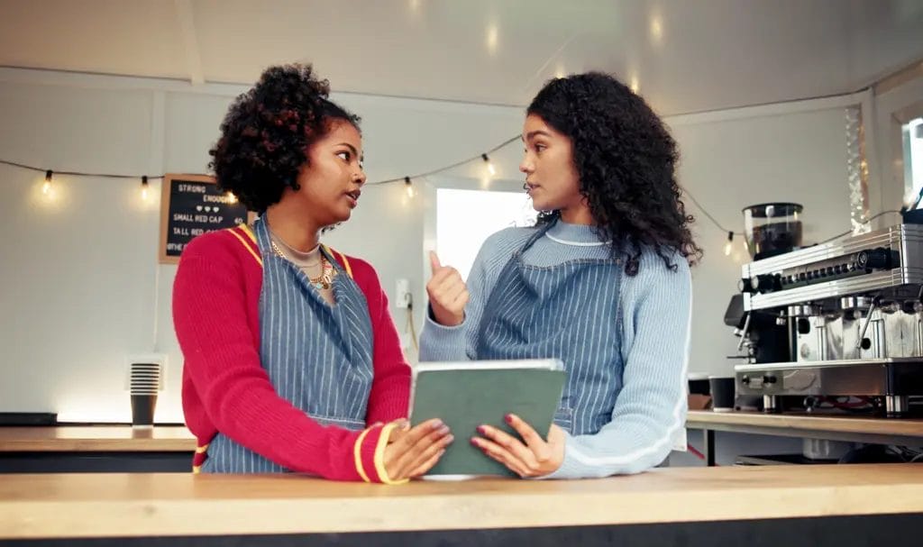 Two young businesspeople discuss paperwork together in their food truck.