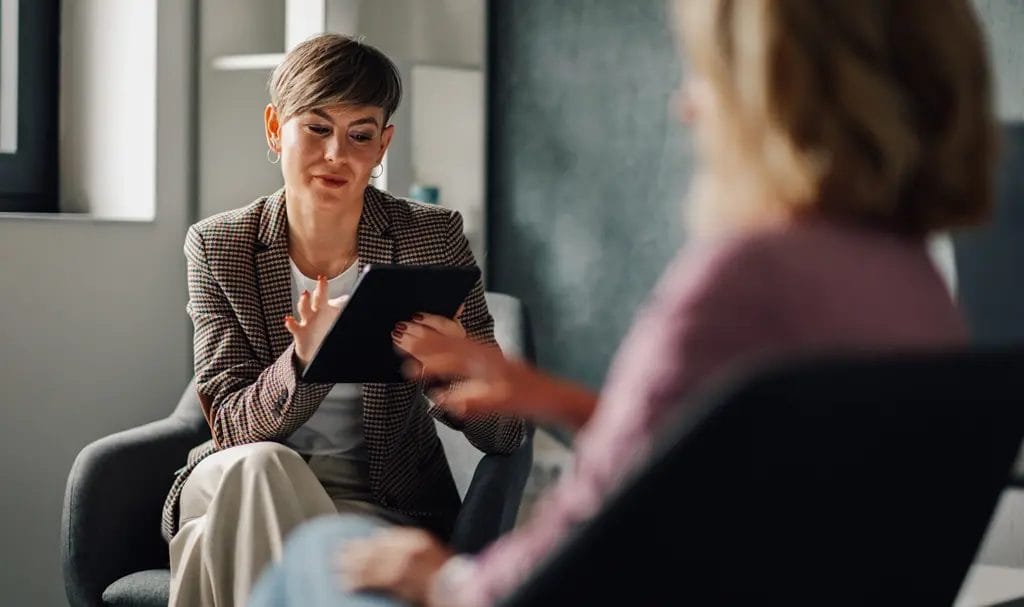 A consultant adds information to a table while meeting with a client.