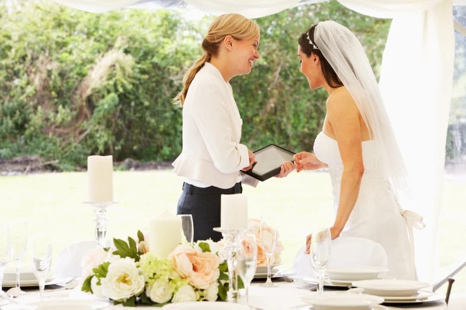 bride talking to a wedding planner under a tent with tables