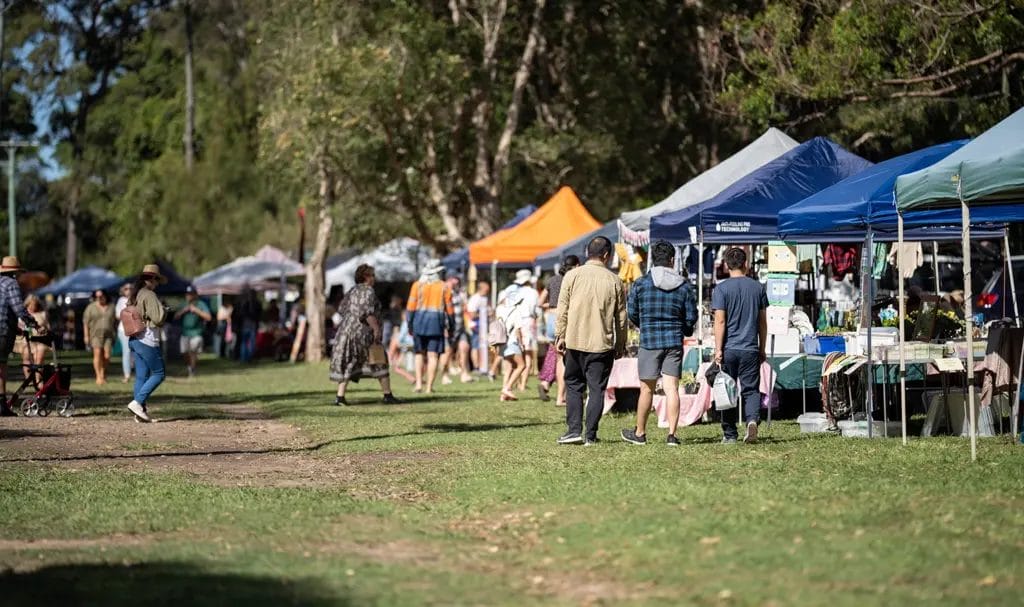 Shoppers are browsing various vendors' booths at an outdoor event.