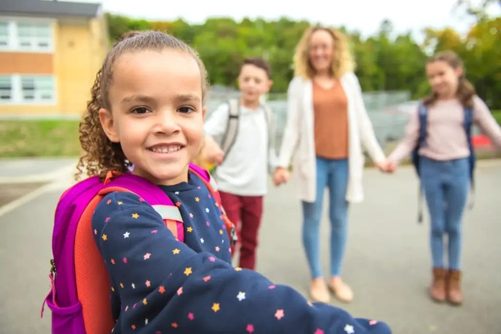 Kids and teacher stand in a circle outside school during recess