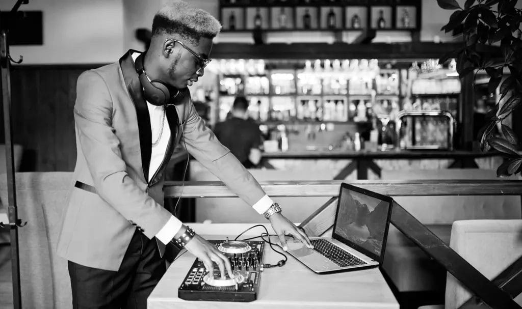 Black and white photo of a DJ setting up his console at a private event.