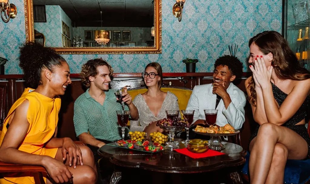 A group of friends laugh and enjoy drinks at a luxurious private dinner event.